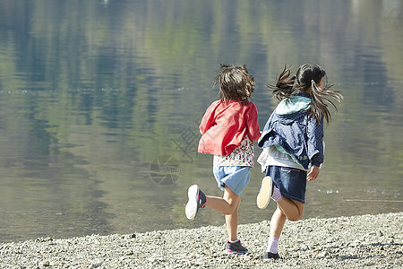 假期户外活动小学生在河边奔跑图片
