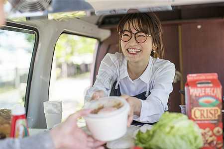 餐车里微笑的递出食物的年轻女性图片