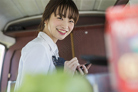 开店选址餐车里拿着手机微笑的年轻女性背景