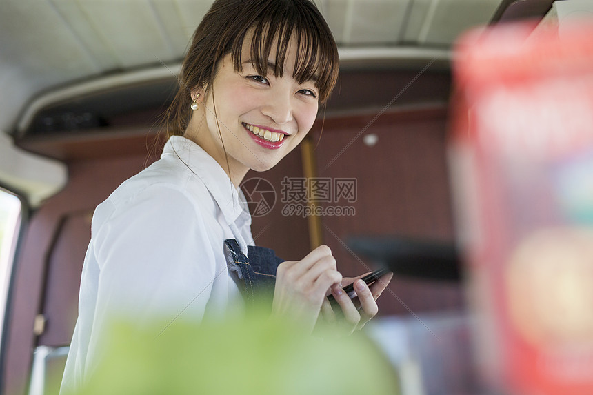 餐车里拿着手机微笑的年轻女性图片