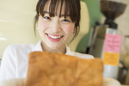 拿着新鲜出炉的面包微笑的年轻女性图片