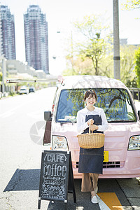 靠在餐车前拿着篮子微笑的年轻女性图片