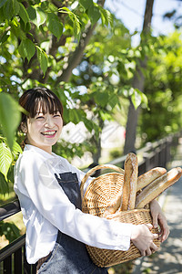 逛商店抱着一筐新鲜面包微笑的年轻女性背景