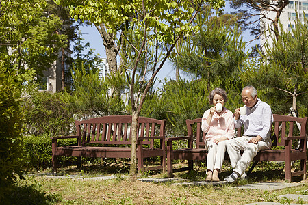 坐在公园长凳上喝茶休息的老夫妇图片