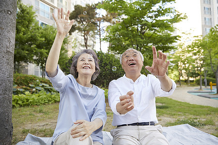 坐在楼下公园草坪上的老年夫妇图片