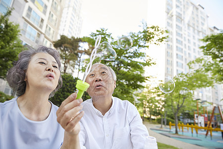 老年夫妇在楼下公园里吹泡泡图片