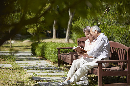 公园长凳上阅读的老年夫妇图片