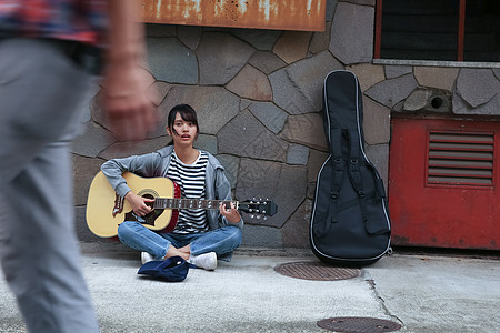 在街头弹吉他卖艺的学生背景图片
