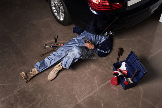 维修汽车躺在地上的汽车维修师图片