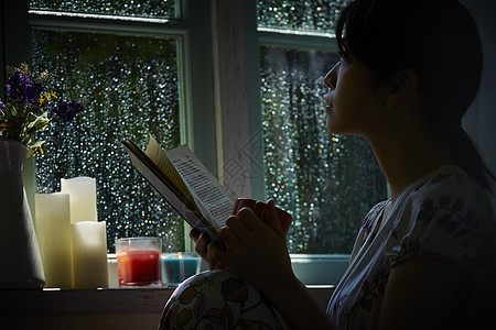 下雨天靠在窗边发呆的孤独女性图片