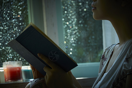 雨夜坐在窗边阅读的女性图片