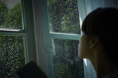 雨夜看向窗外的女青年背景图片