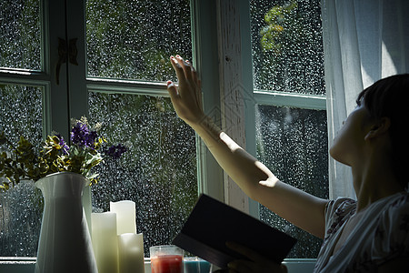 下雨天看向窗外的年轻女性图片