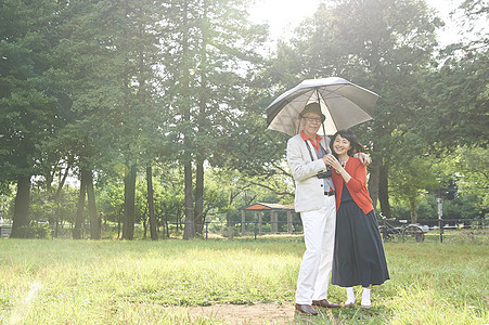 公园里撑着伞遮阳开心的夫妇图片