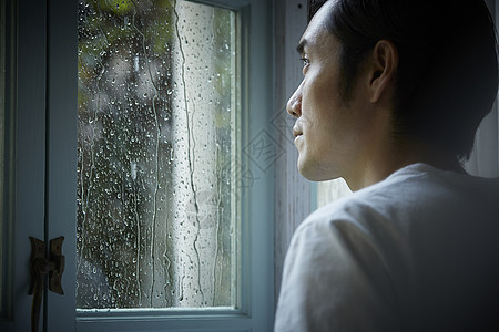 雨天看着窗外的成年男子图片