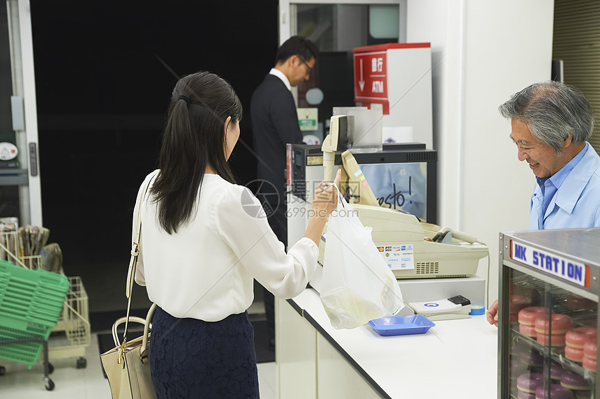 便利店收银台拿着购物袋的女性背影图片