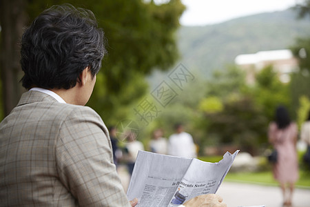 户外看报纸的的成年男子背影图片素材