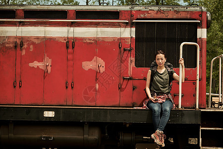 注视镜头女人背包在废弃火车前图片