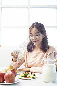 年轻女人微笑的吃着早餐图片