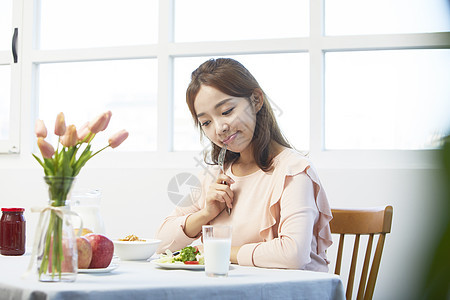 看着餐桌上的食物歪头的年轻女性图片