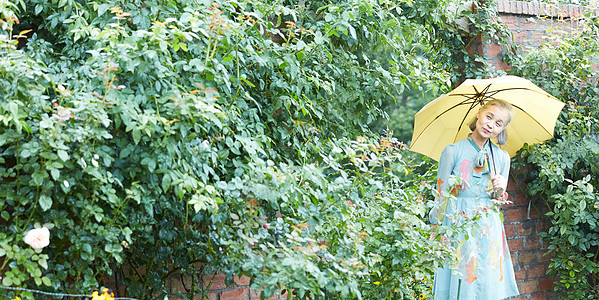 拿着一把伞的老年妇女在庭院里图片