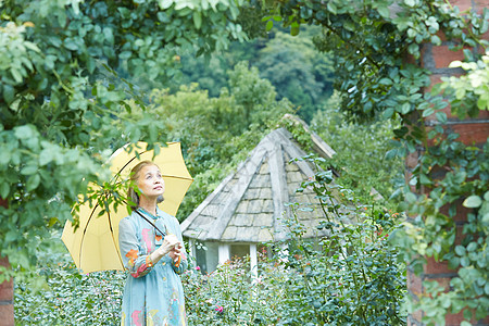拿着遮阳伞在庭院里的老妇人图片