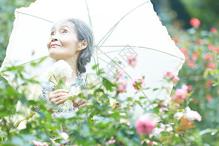 花园里拿着遮阳伞的老年人图片