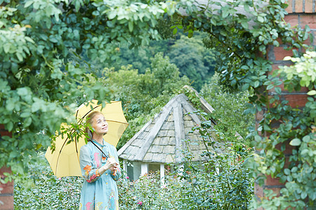 在庭院里散步打着伞的老妇人图片