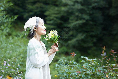 避暑胜地拿着花束嗅闻的老年女性背景