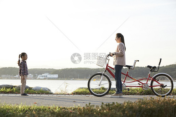 母女推行双人自行车游览公园图片