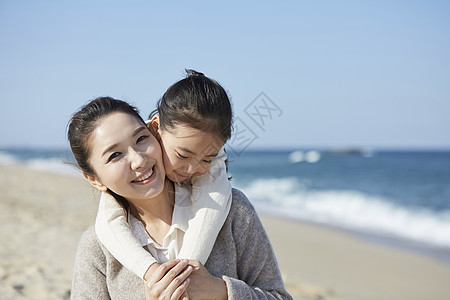 海边沙滩上在妈妈背上的女孩高清图片