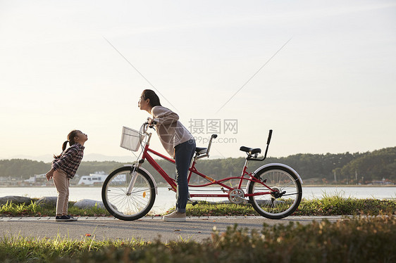 母女推行双人自行车游览公园图片