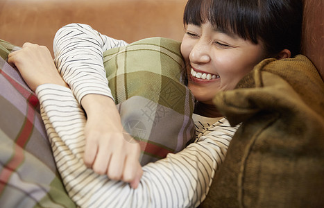 一个女人抱着抱枕躺在沙发上图片