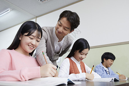 孩子写作业老师在教室里指导学生写作业背景