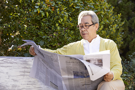 老人在室外看报纸背景