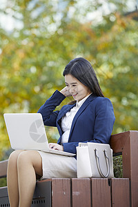 坐在长凳上工作的女青年图片
