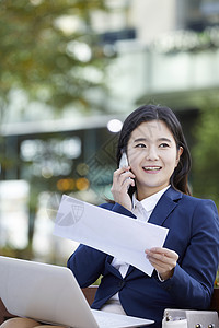 户外拿着文件打电话的职业女性图片