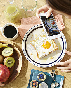 用手机拍摄自制早餐的职业女性图片