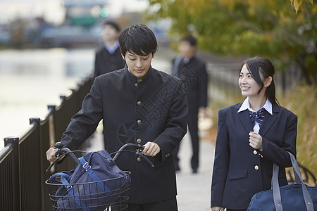 推着自行车走在上下学路上聊天的日本学生图片