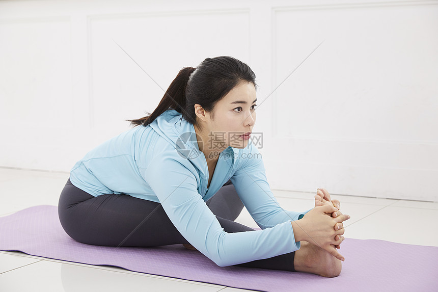 穿着运动服在瑜伽垫上拉伸的年轻女子图片