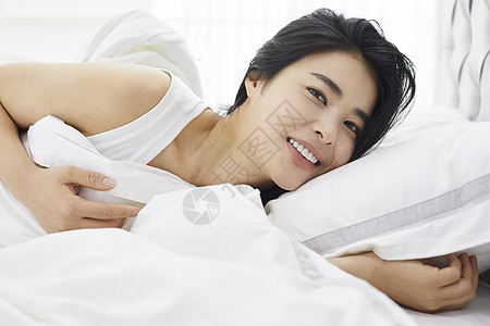 床上微笑的青年女性休息高清图片素材