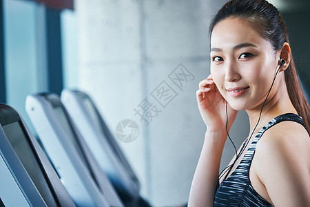 青年笑脸青春健身房跑步机的女人图片