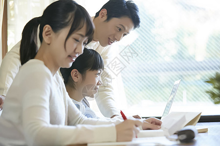 用笔记本电脑的女孩和父母一起学习图片