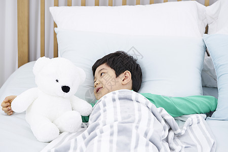 床上抱着小熊的男孩洋娃娃高清图片素材