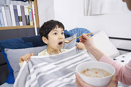 妈妈照顾小男孩吃粥背景图片