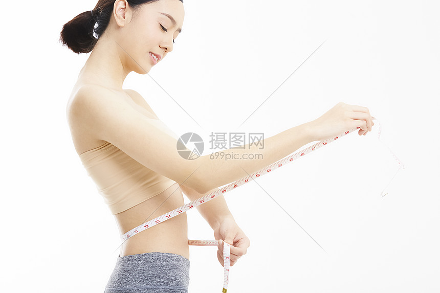 年轻女子拿着软尺测量腰围图片