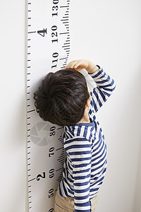 测量身高看着刻度的小男孩图片