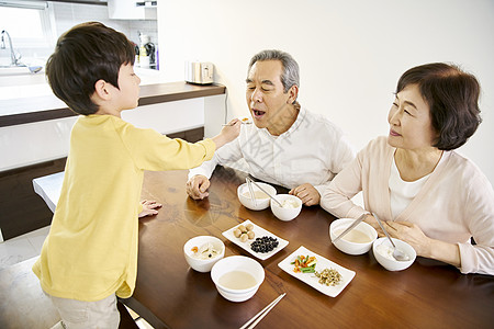 餐桌上吃饭的祖父母和孙子高清图片