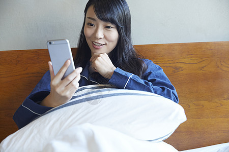 坐在床上看手机的青年女子图片