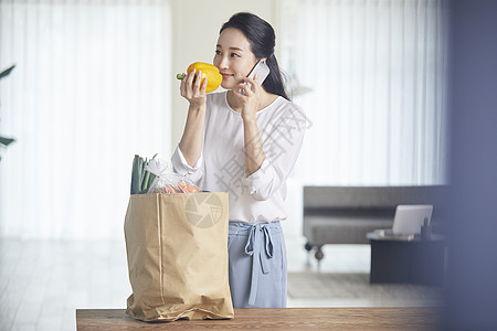 青年女子拿着手上的甜椒接电话图片